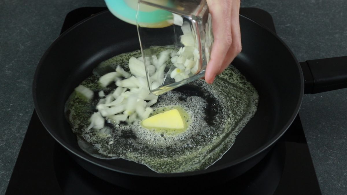 onions being poured into skillet with butter