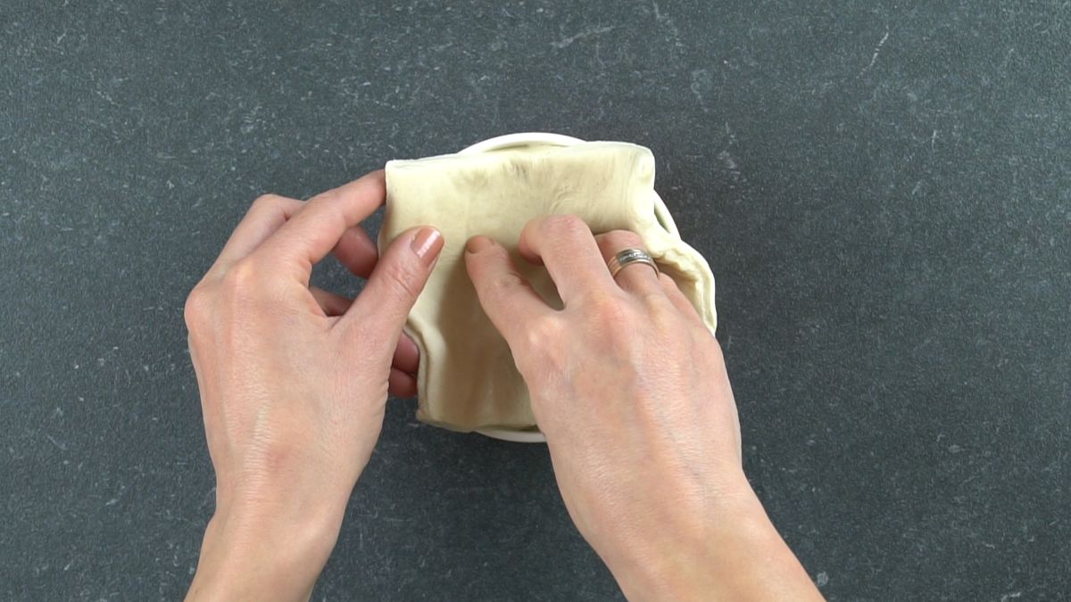 hand putting pastry into ramekin