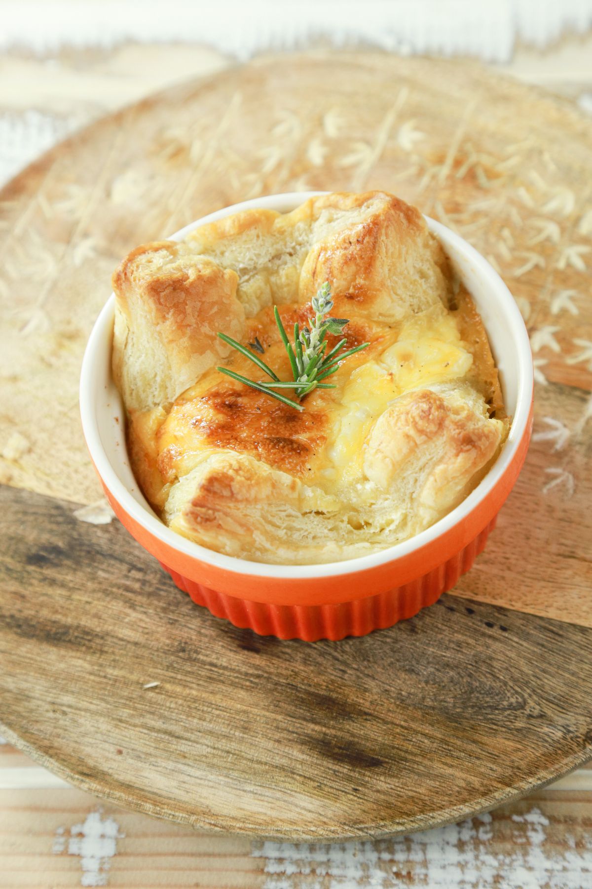orange ramekin filled with puff pastry quiche on wood table