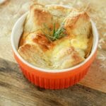 orange ramekin filled with puff pastry quiche on wood table