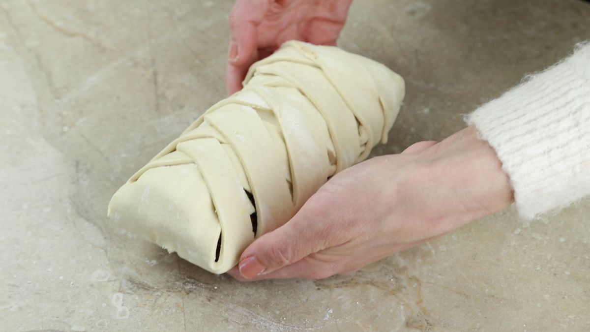 hands holding braided dessert bread before baking