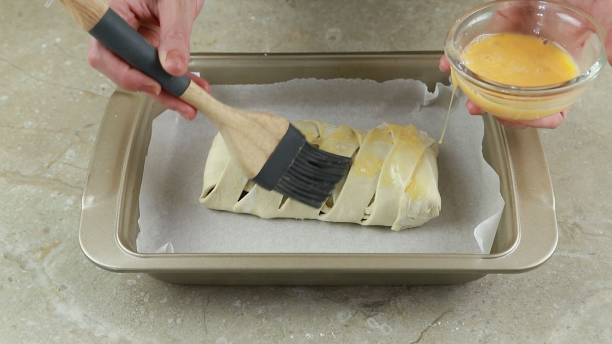 hand brushing pastry with egg wash