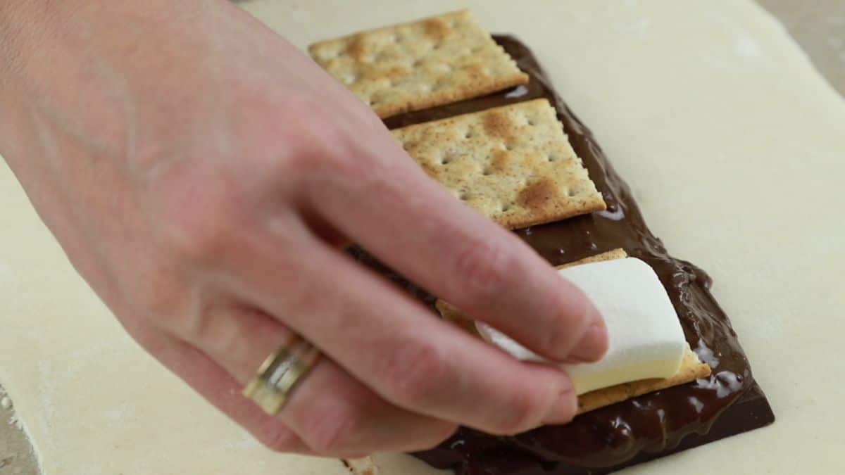 hand putting marshmallows on top of graham crackers