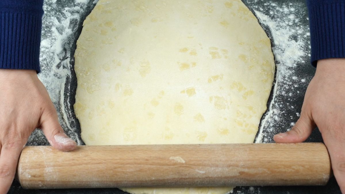 rolling pin rolling out dough onto black table
