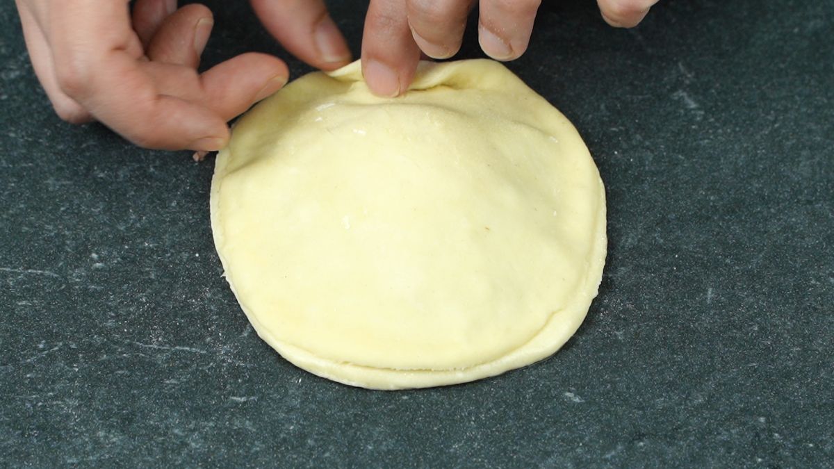 hand crimping edges of dough round