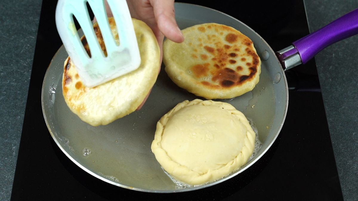 teal spatula turning stuffed pancakes in skillet