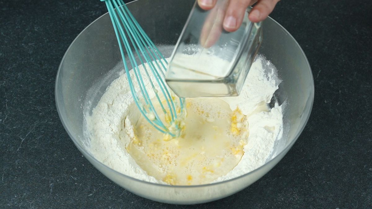 water being poured into bowl of flour