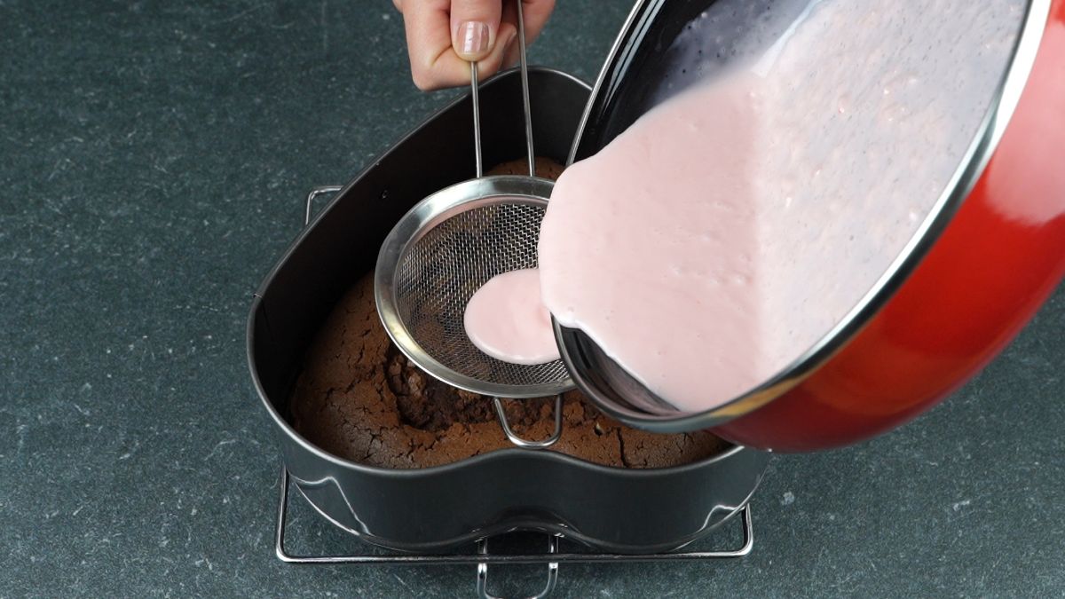 strawberry gelatin being poured over chocolate cake