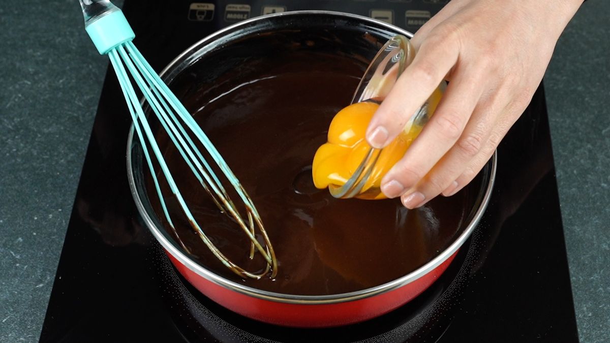hand adding eggs into chocolate