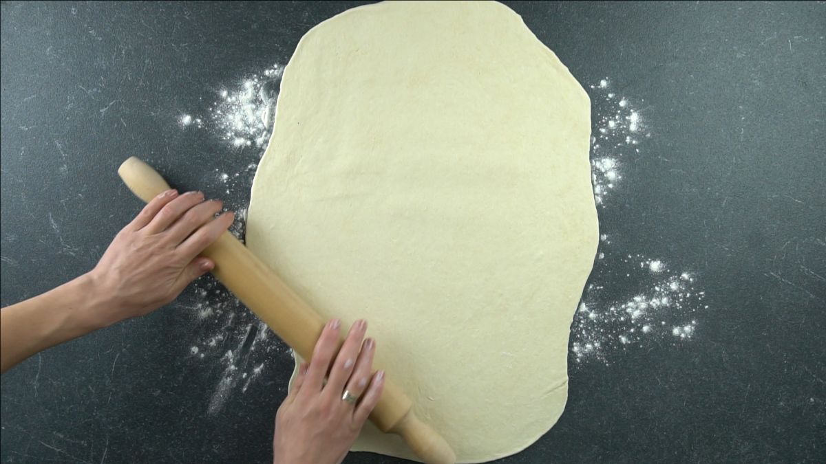 hand rolling dough out onto table