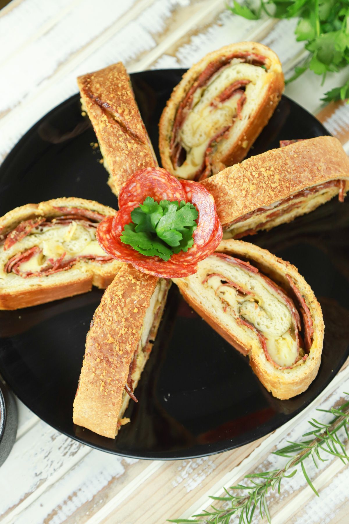 round black plate holding stromboli slices with pepperoni rose in the center