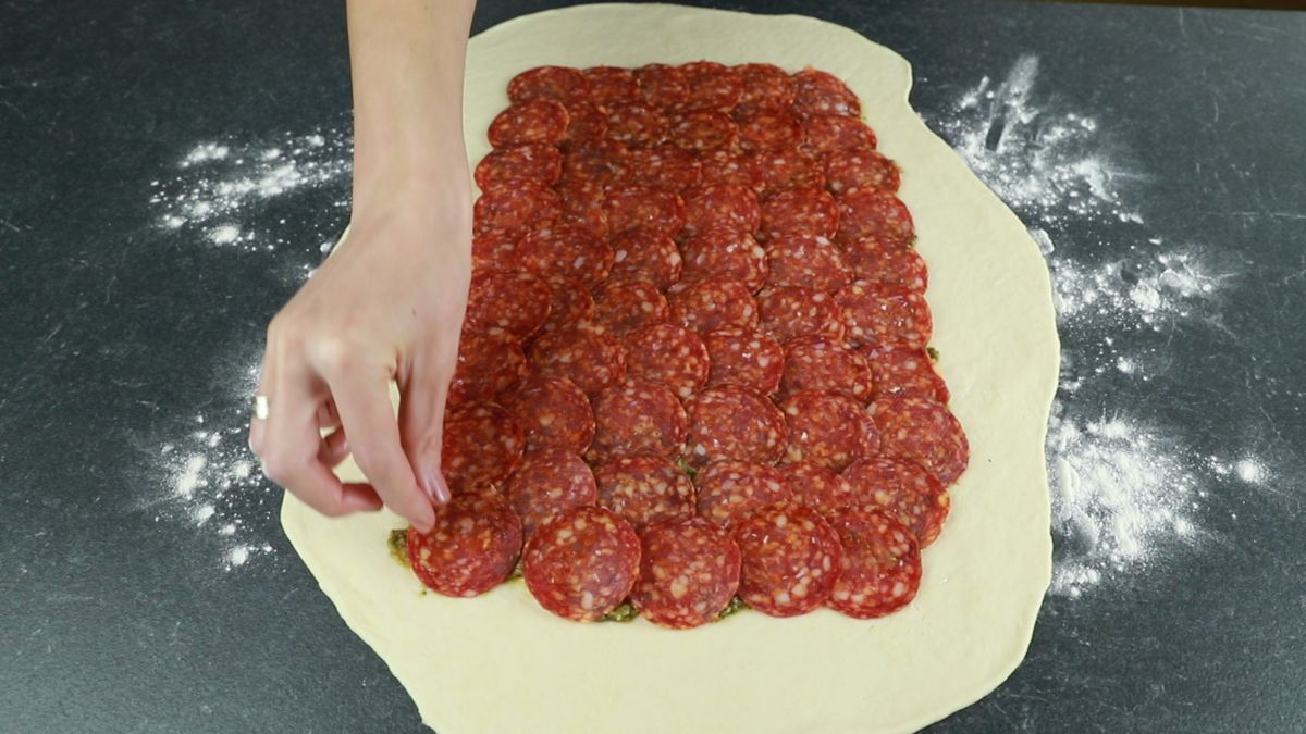 pepperoni laying over the top of pizza dough