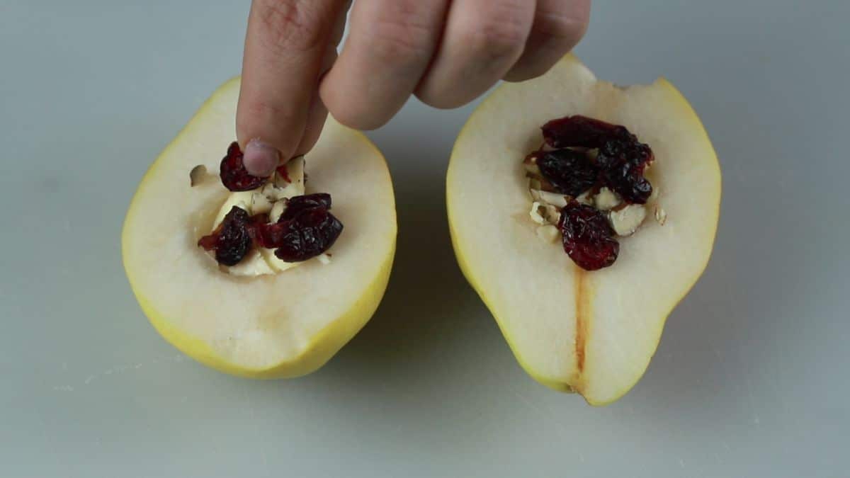 nuts being put on top of pear halves