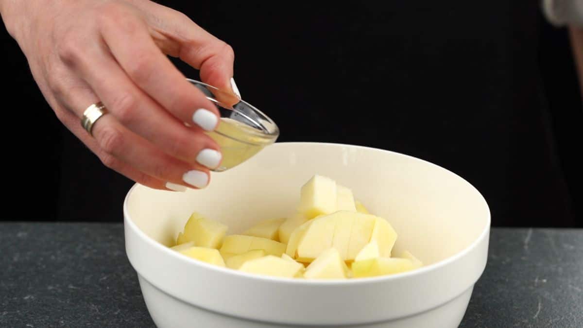 apples in white bowl with lemon juice being poured over the top