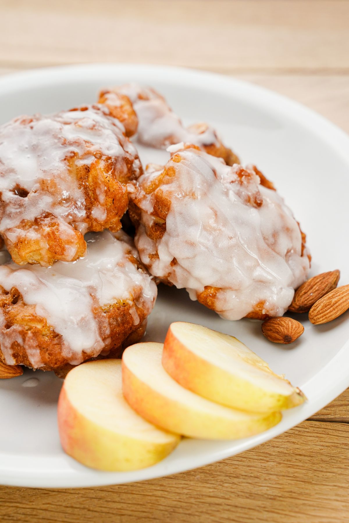 white plate of apple fritters with glaze