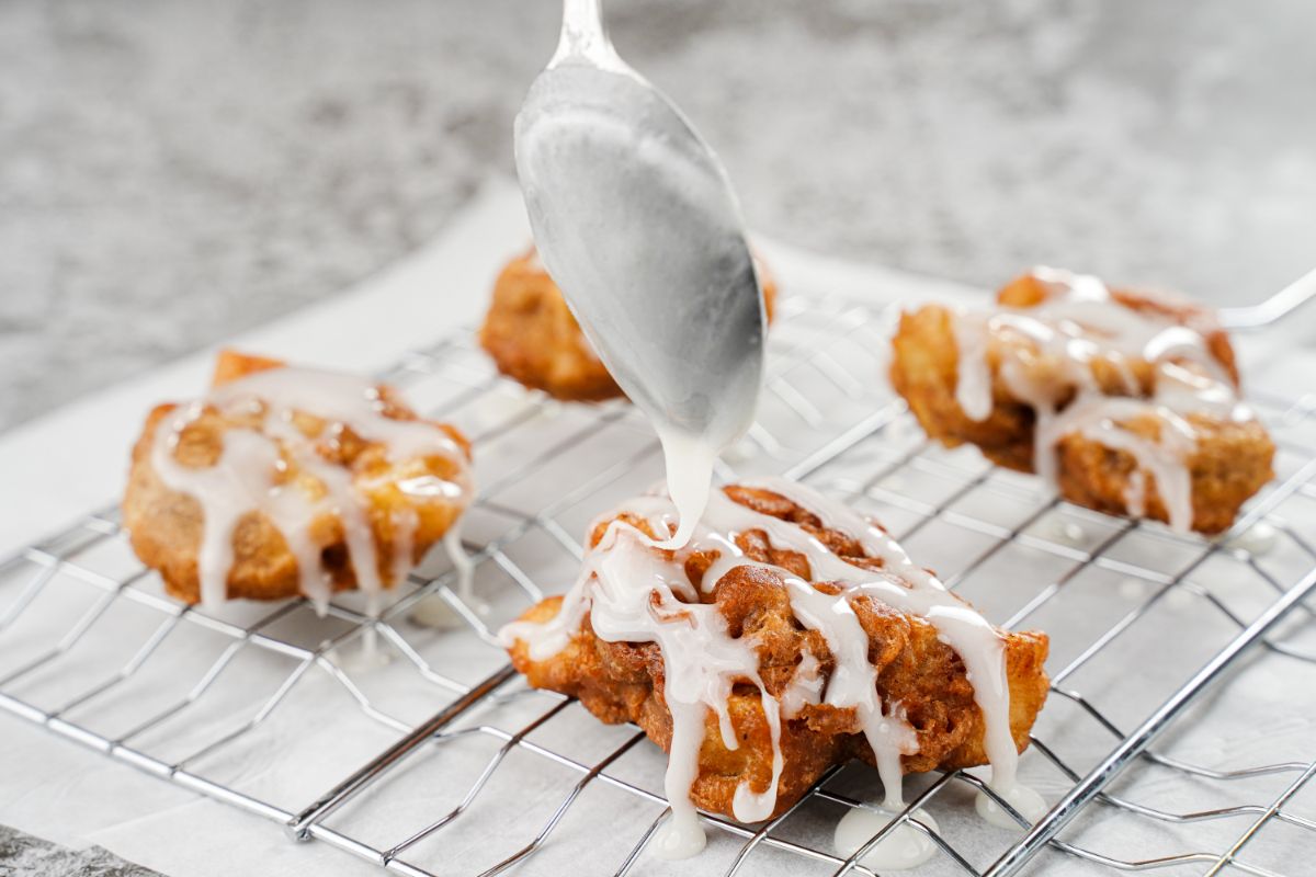spoon holding glaze over fritters on rack