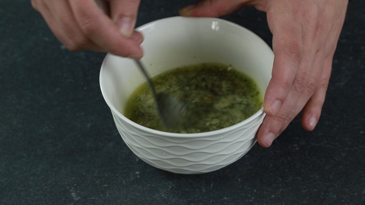 fork in white bowl whisking herbs with butter