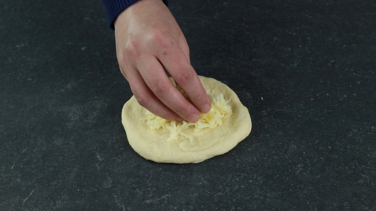 hand adding cheese on top of dough