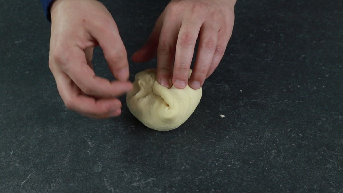 fingers pinching dough around cheese