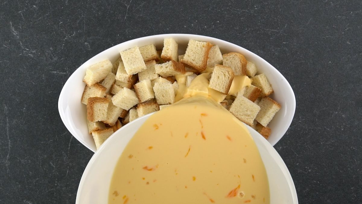 egg custard being poured over baking dish of bread pieces