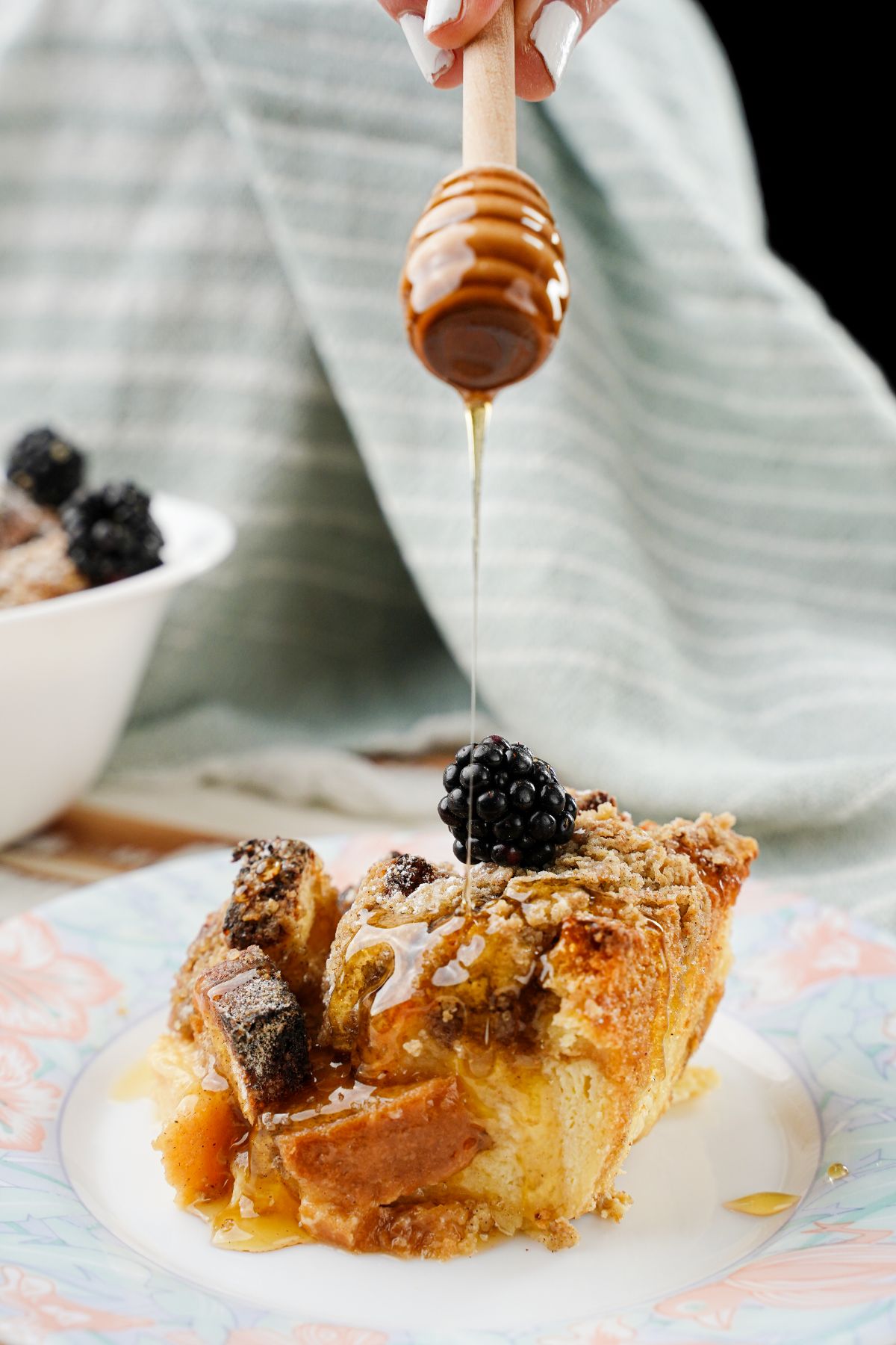 hand holding honey wand above plate of french toast bake