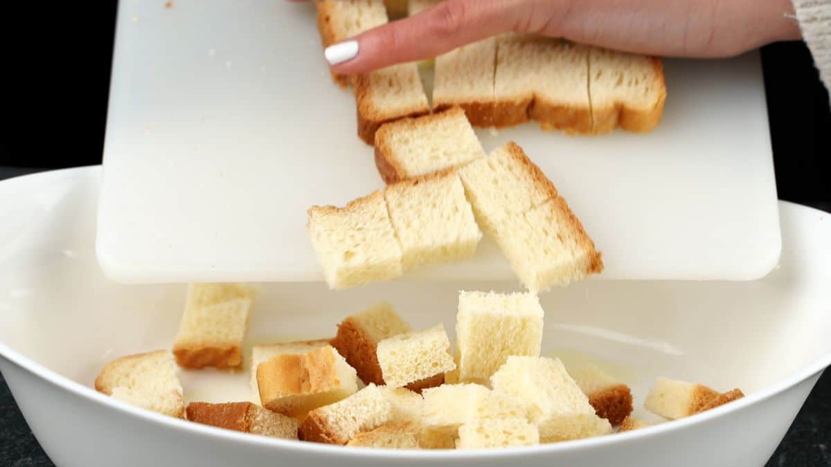 bread pieces being poured into a white bowl