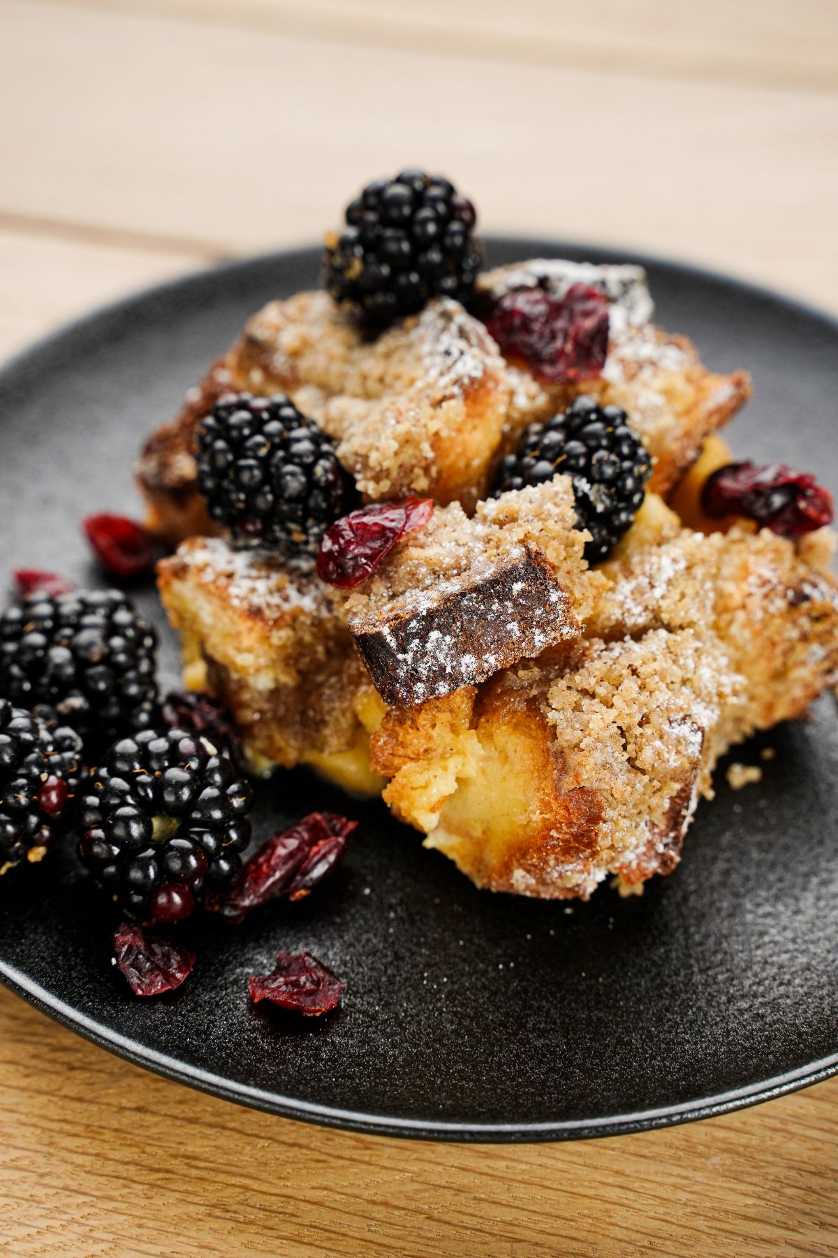 french toast bake topped with berries on black plate