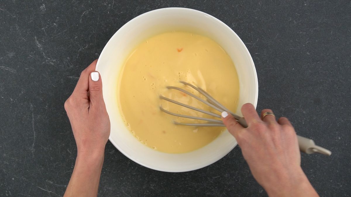 whisk in white bowl with egg and milk