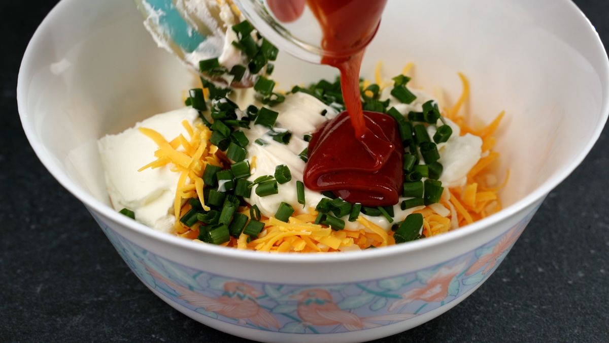 hot sauce being poured into white bowl of sauces