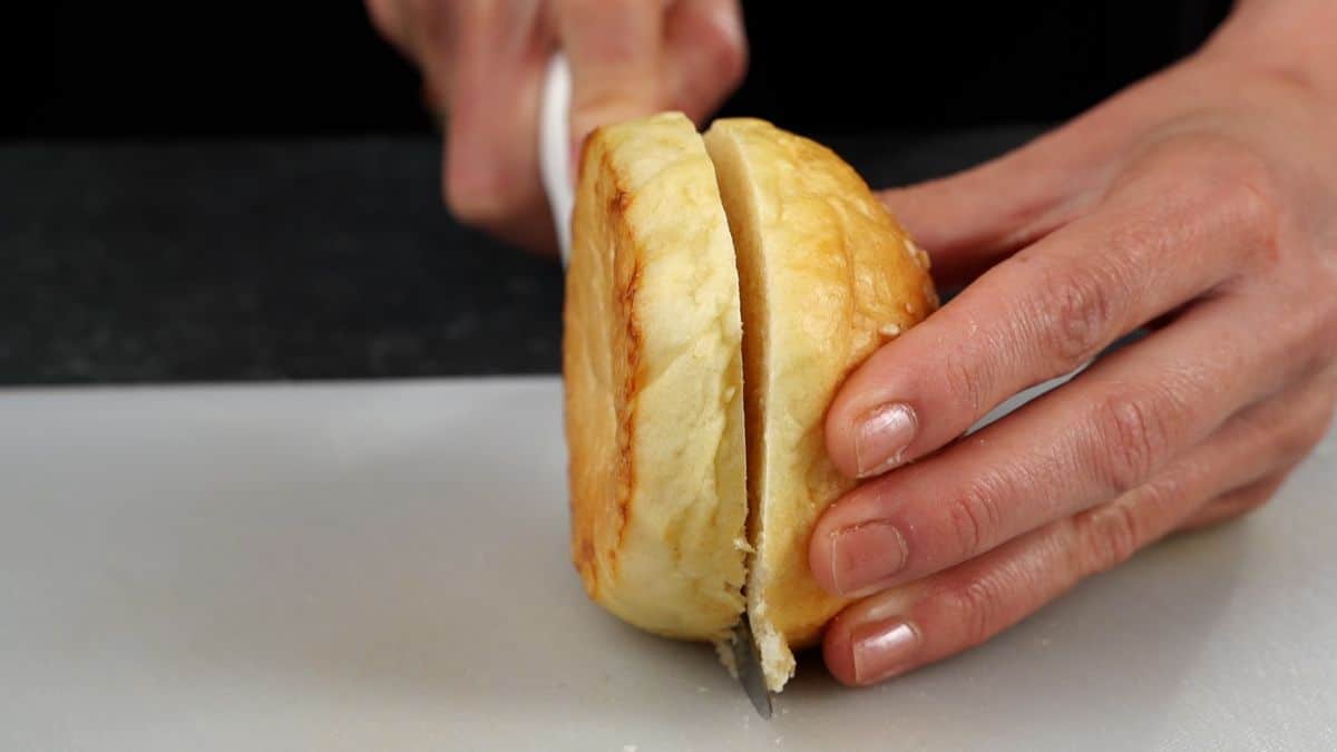 hand slicing bun on cutting board