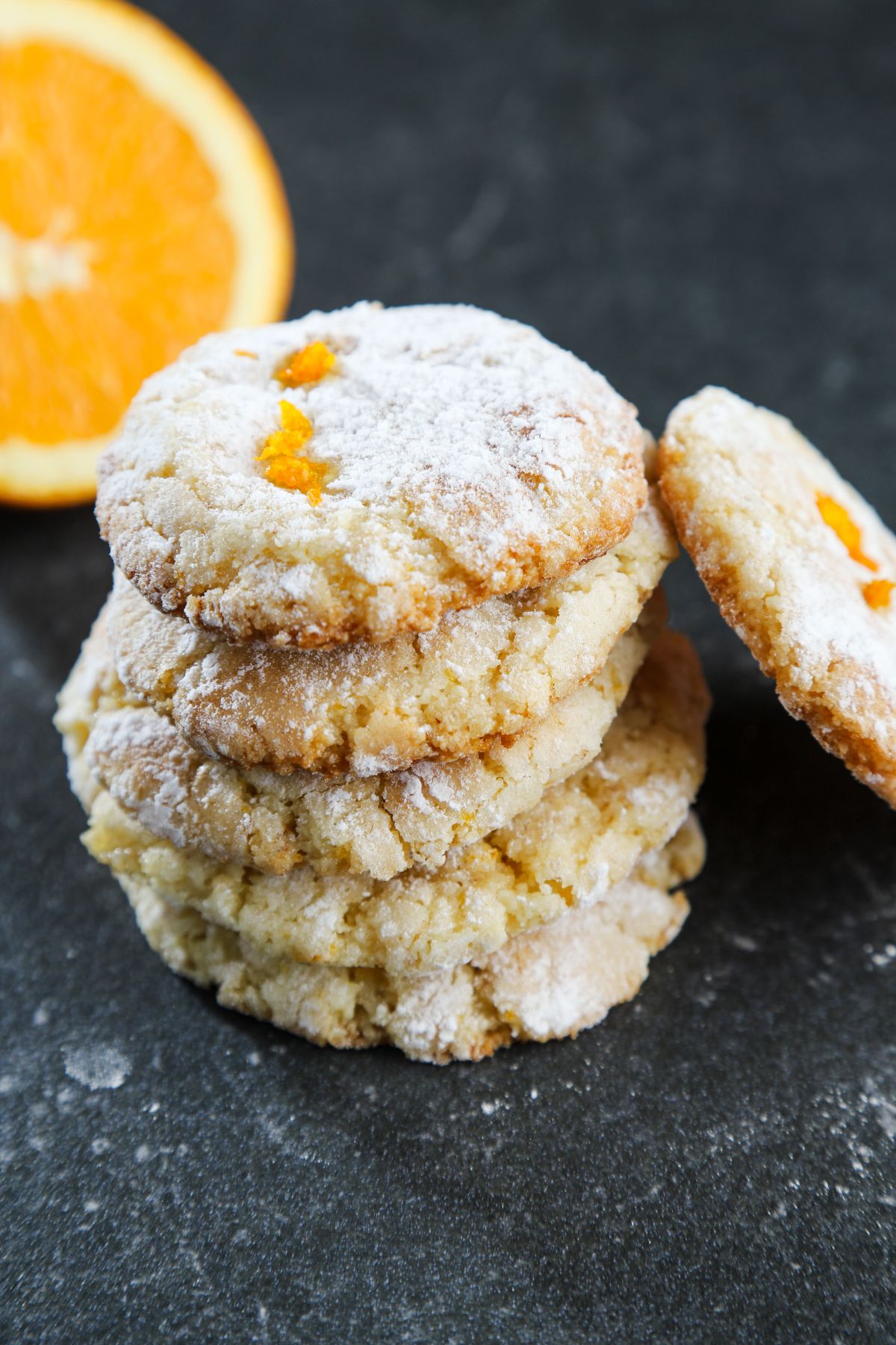orange cookies with a single cookie leaned against stack and orange in background