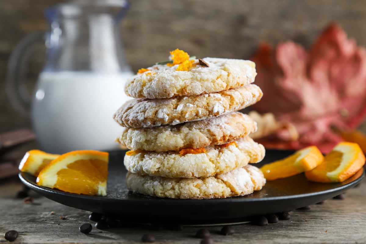 stack of almond cookies on brown bowl with milk in background