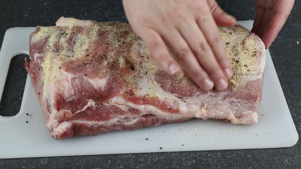 hand rubbing seasoning into pork
