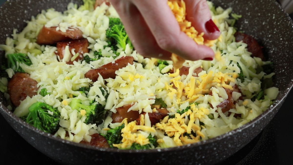 hand sprinkling cheese over rice in skillet