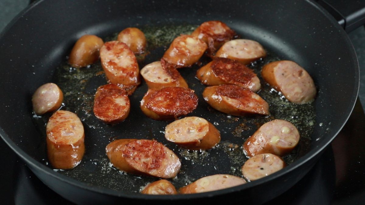 browned sausage pieces in speckled black skillet
