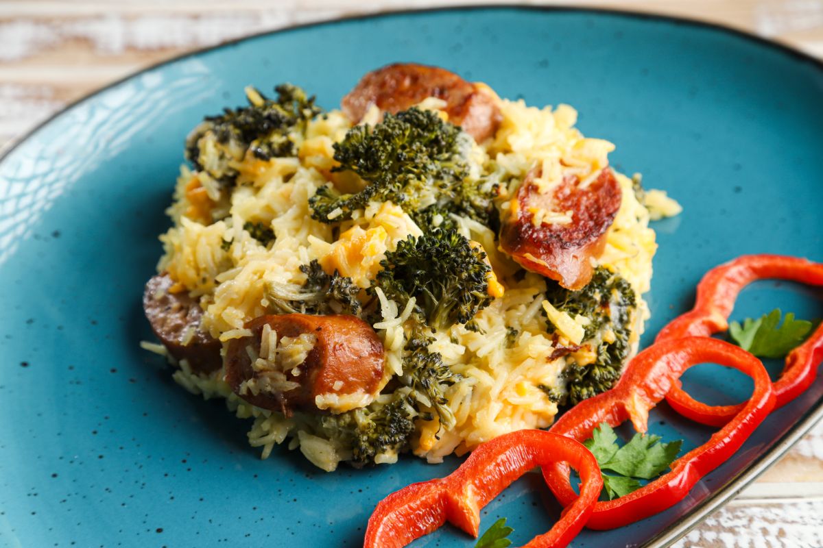 teal bowl with spoon of rice with broccoli and sausage