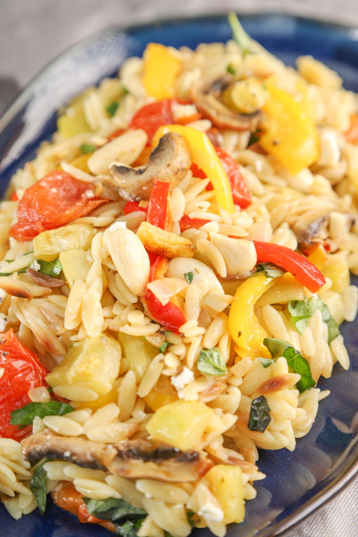 blue platter of orzo loaded with roasted vegetables
