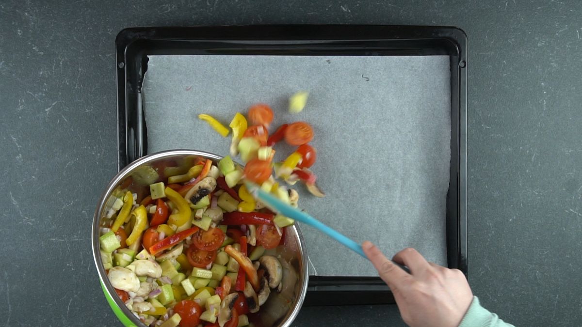 spoon scooping vegetables onto baking sheet
