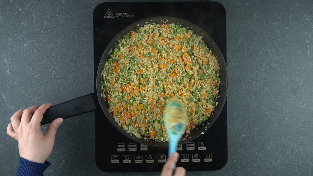 skillet on hot plate holding cauliflower rice and vegetables