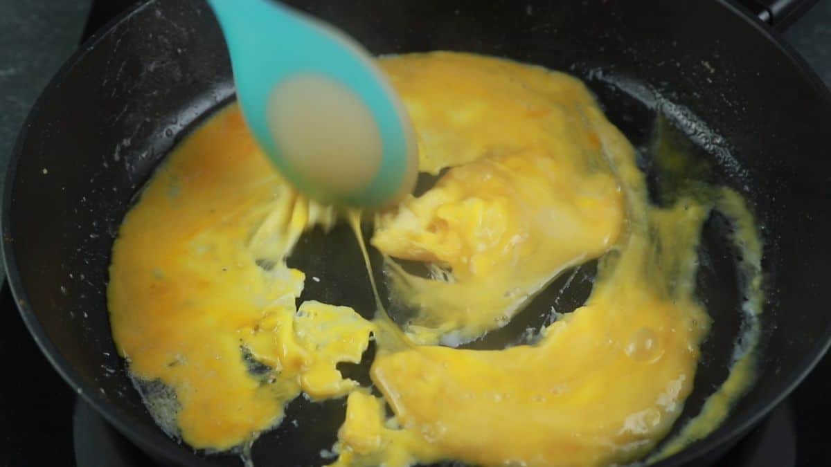 blue spoon in eggs in skillet