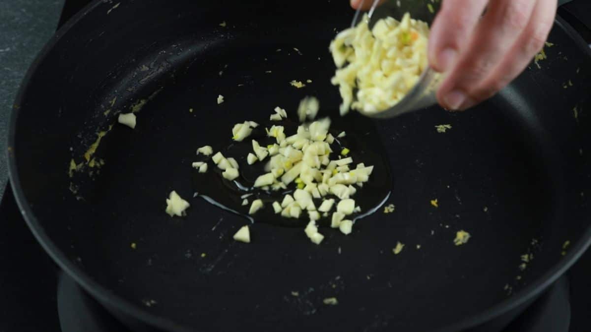 garlic being poured into black skillet