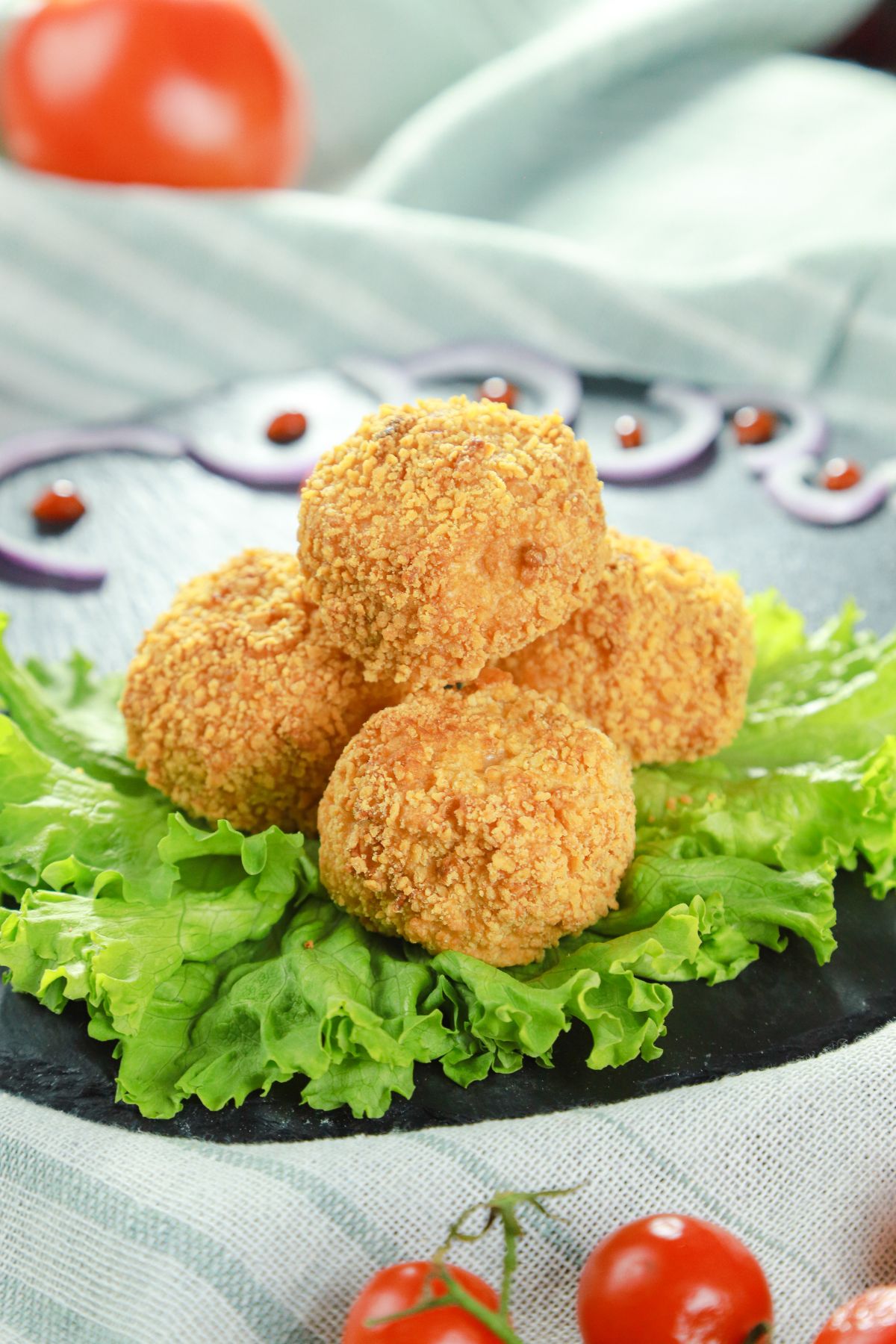 stack of fried chicken balls on bed of lettuce on striped napkin