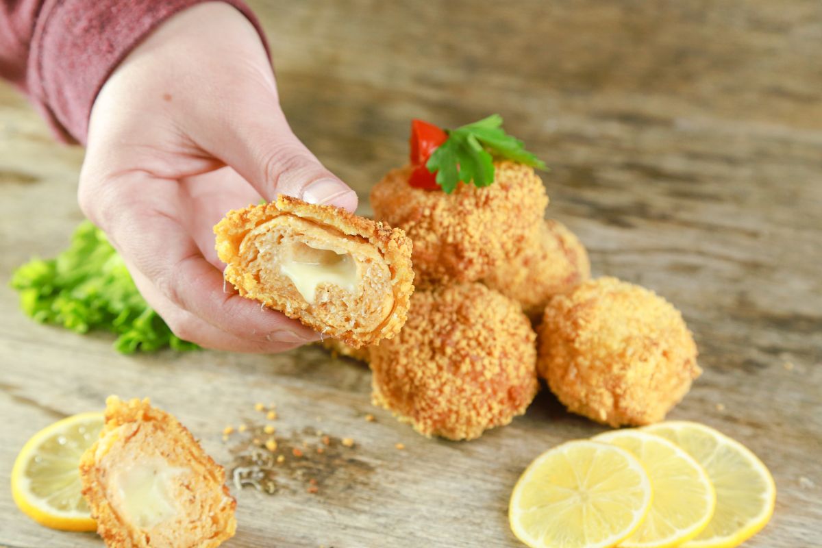 hand holding chicken ball cut open with cheese in middle