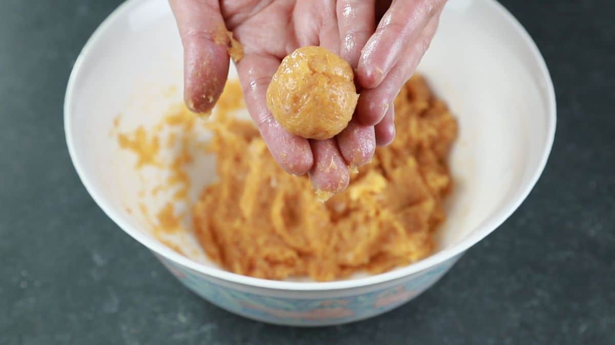 hand holding chicken bomb above bowl of raw chicken