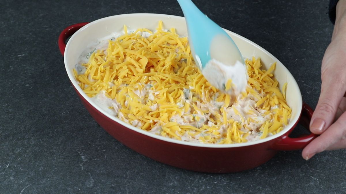 blue spoon on top of oval dish of buffalo chicken dip