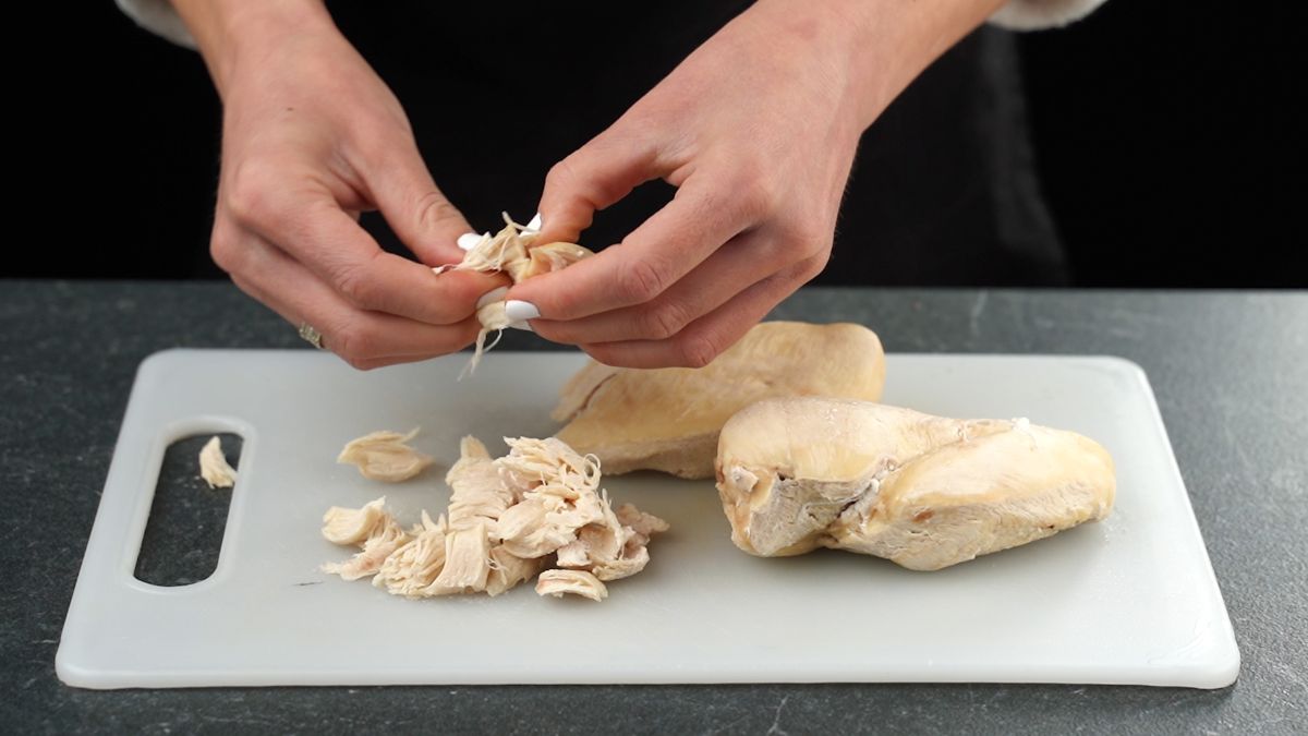 hand pulling cooked chicken apart
