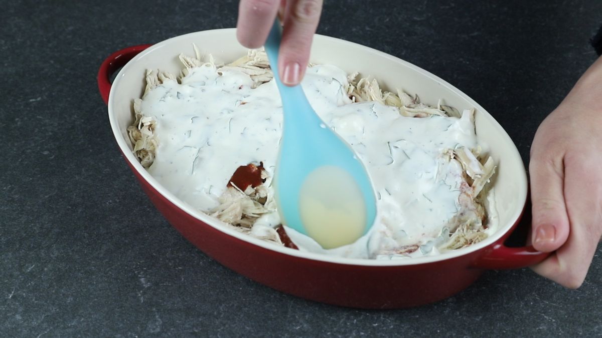 blue spoon stirring dip in baking dish