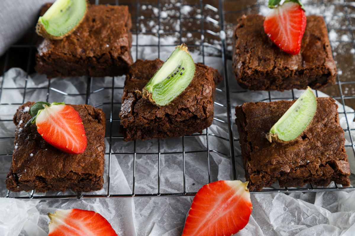 brownies on wire rack topped with sliced strawberries and kiwi