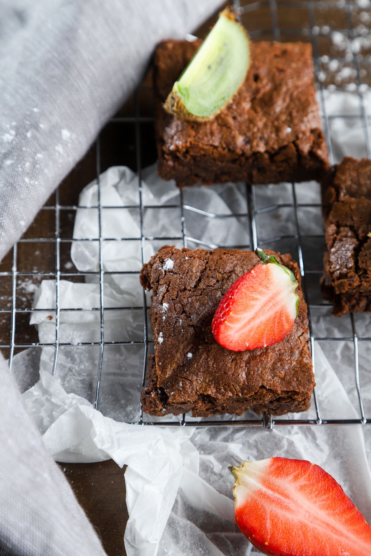 brownies with fruit slices on top of wire rack on white paper