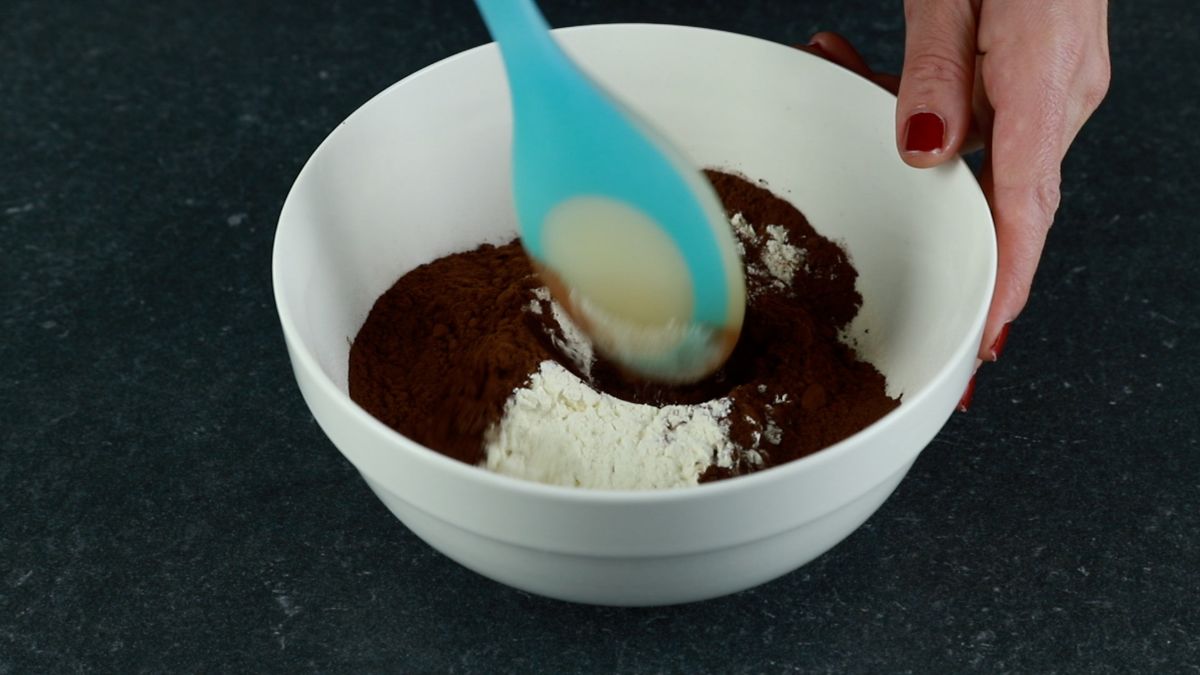blue spoon stirring cocoa powder into flour